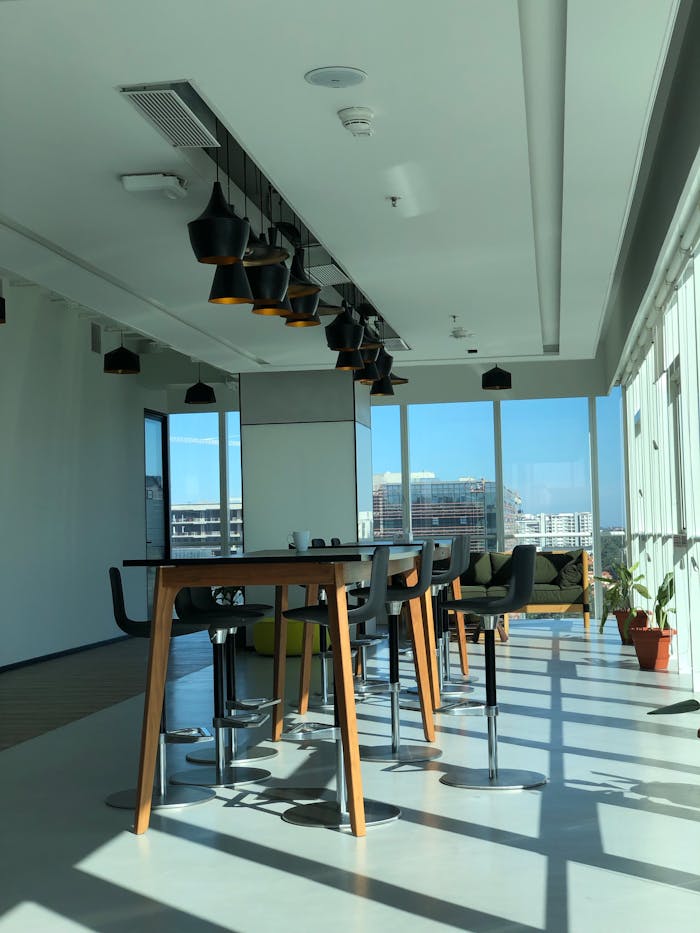 Spacious sunlit office interior featuring contemporary furniture and large windows.