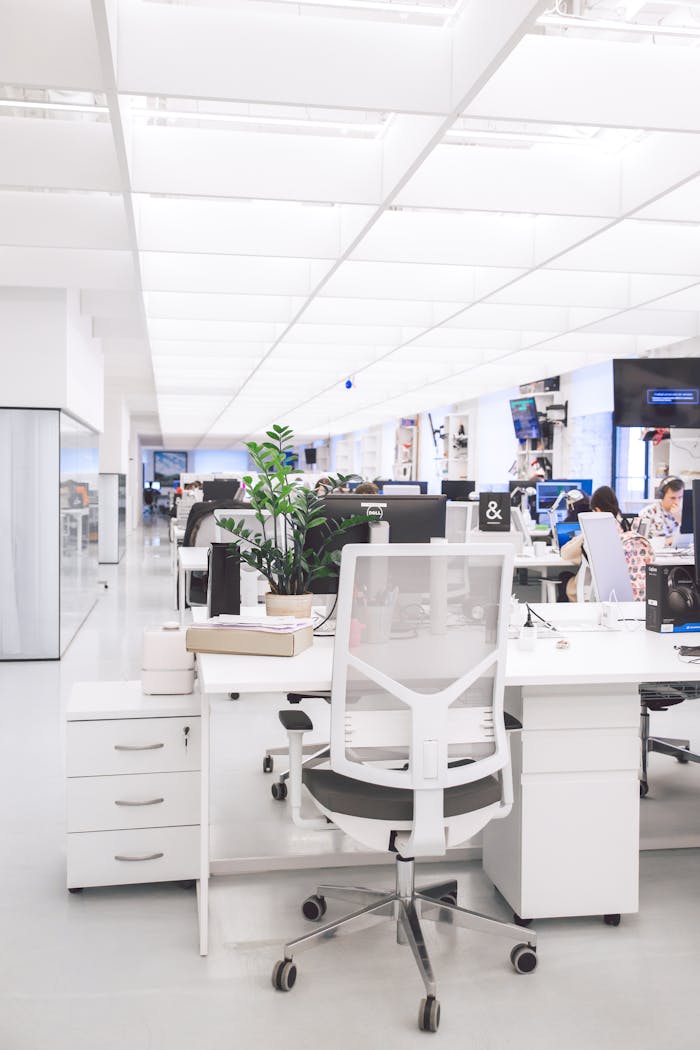 Bright modern office interior with desks, chairs, and computers in an open-plan workspace.