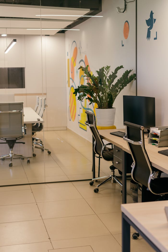 Spacious and contemporary office interior with glass partitions, stylish furniture, and vibrant wall art.